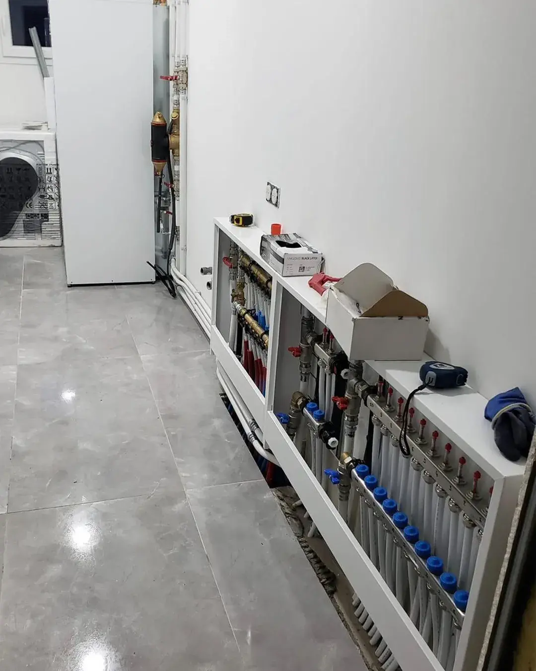 Installation de radiateurs et tuyauterie de chauffage dans une maison, avec panneaux de contrôle bleus et accessoires de