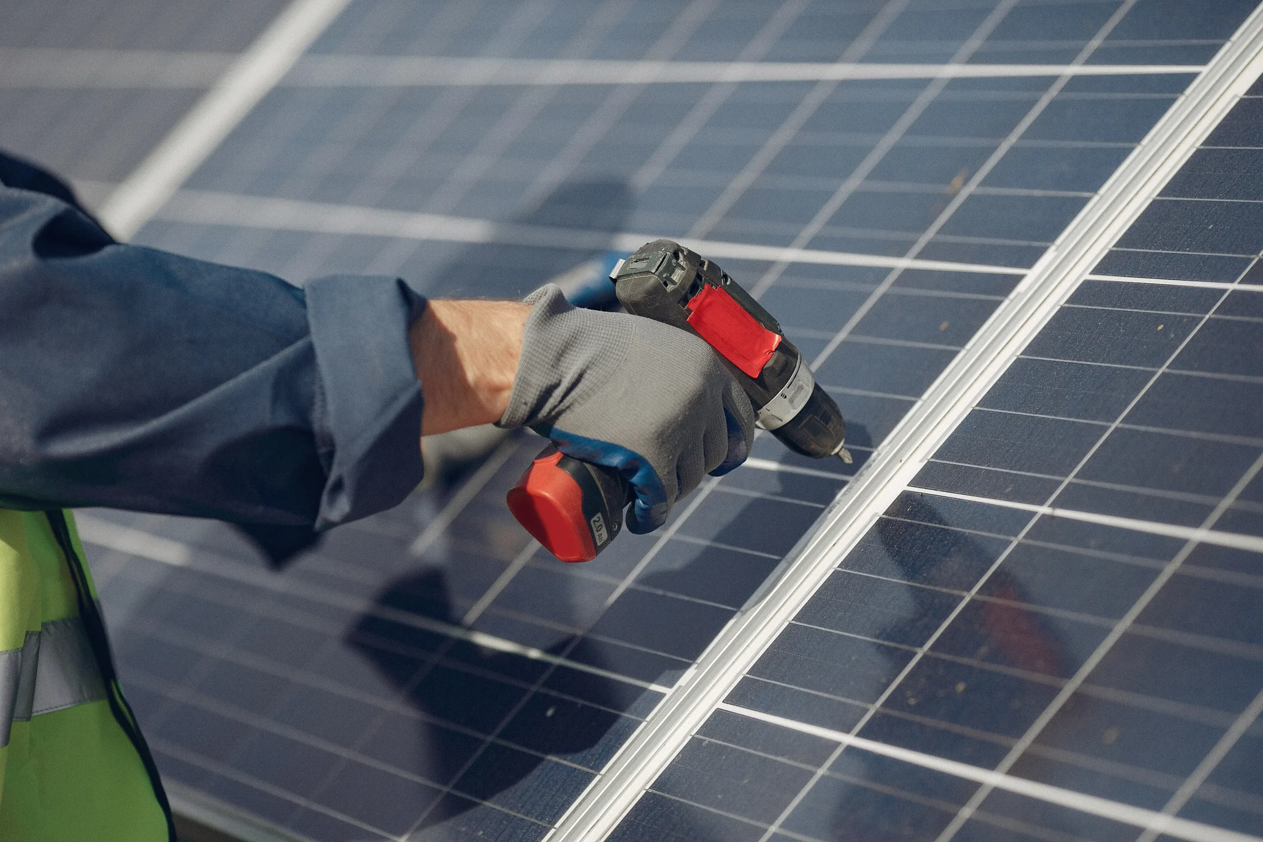 Technicien installant un panneau solaire photovoltaïque avec une perceuse-visseuse sur une toiture